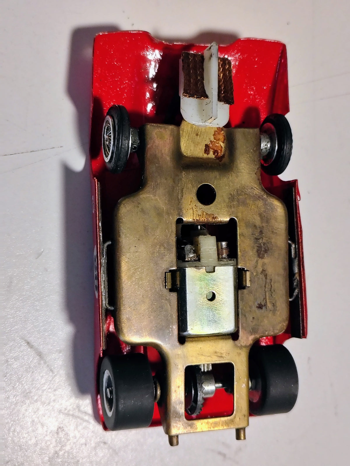 Close-up red Ti-22 vintage slot car brass chassis, motor and gearing